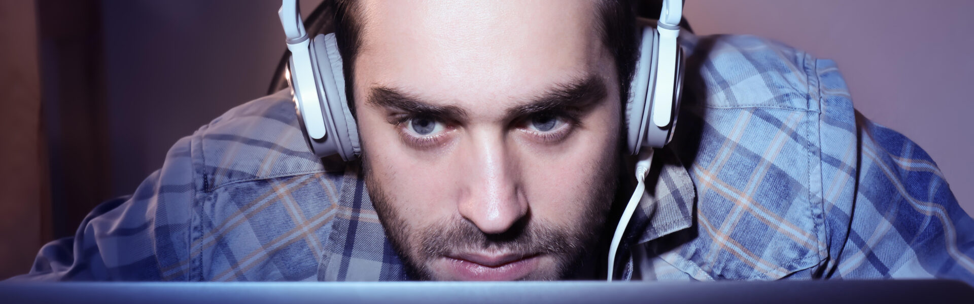 a man leaning into the monitor with a headset on while playing the intense roguelite The King is Watching