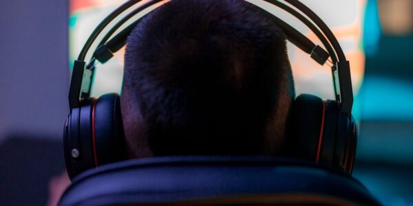 a back view of a person wearing headphones in front of a PC playing Avowed