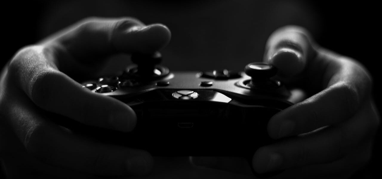 a person holding an X Box controller while playing The First Berserker: Khazan in the dark