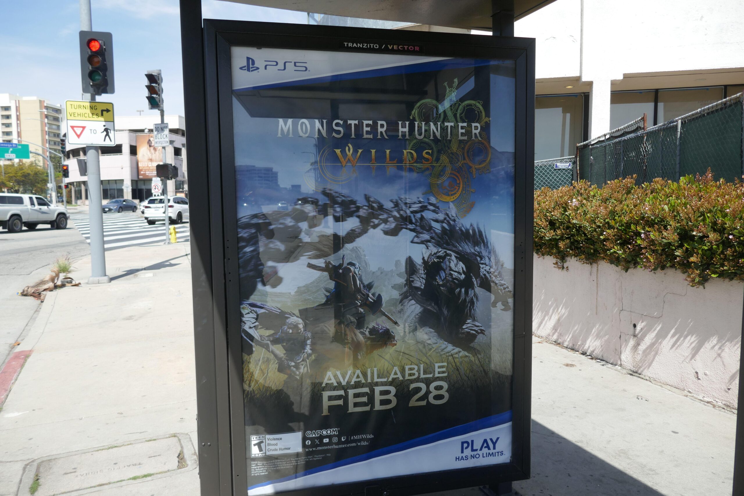 a billboard on the street that promotes Monster Hunter Wilds for Playstation 5