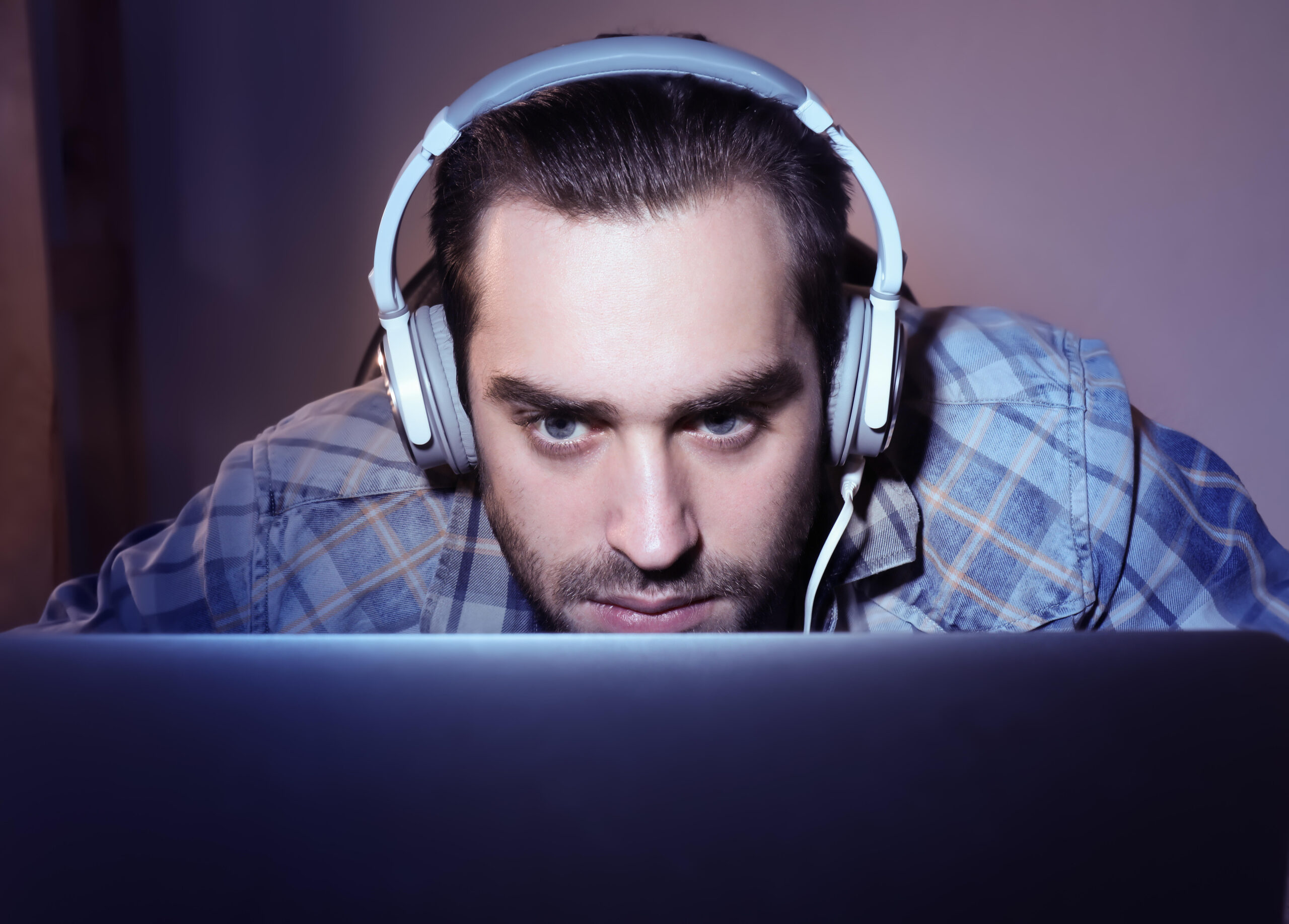 a man leaning into the monitor with a headset on while playing the intense roguelite The King is Watching